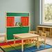 a preschool play area with puppets, table, chairs, and a rug.