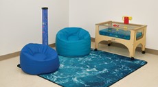 A collection of ocean-theme classroom furniture and accessories including an ocean rug, blue beanbag chairs and a water play station